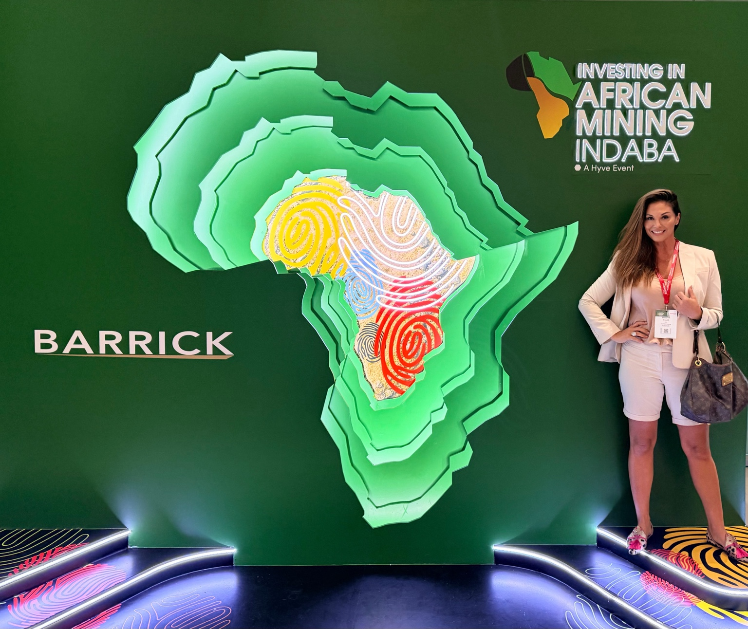 Adrienne Westman at the Investing in African Mining Indaba, beside a Barrick Africa display